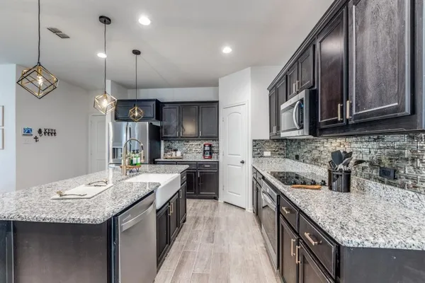 a kitchen with granite countertop kitchen island stainless steel appliances a sink stove and cabinets