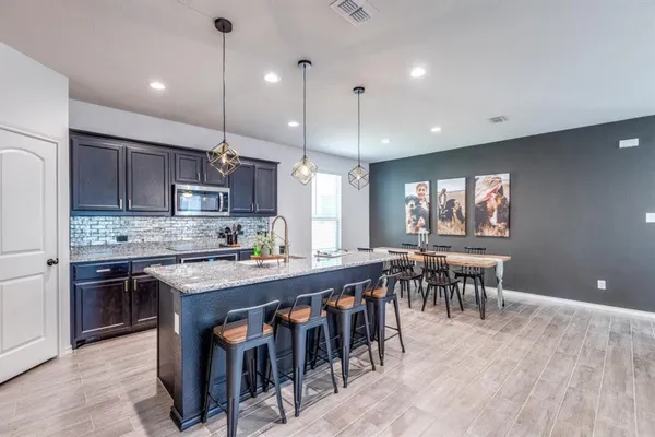 a kitchen with kitchen island a dining table chairs and white cabinets