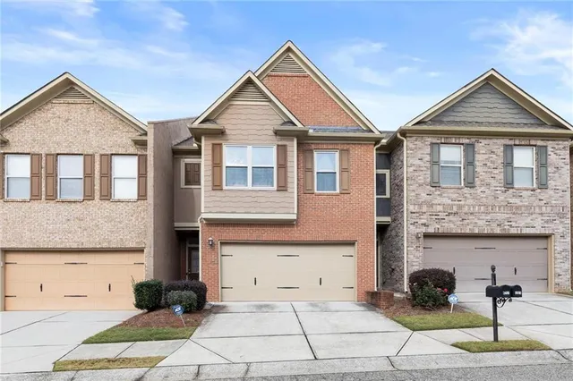 a view of a brick house with yard and parking space