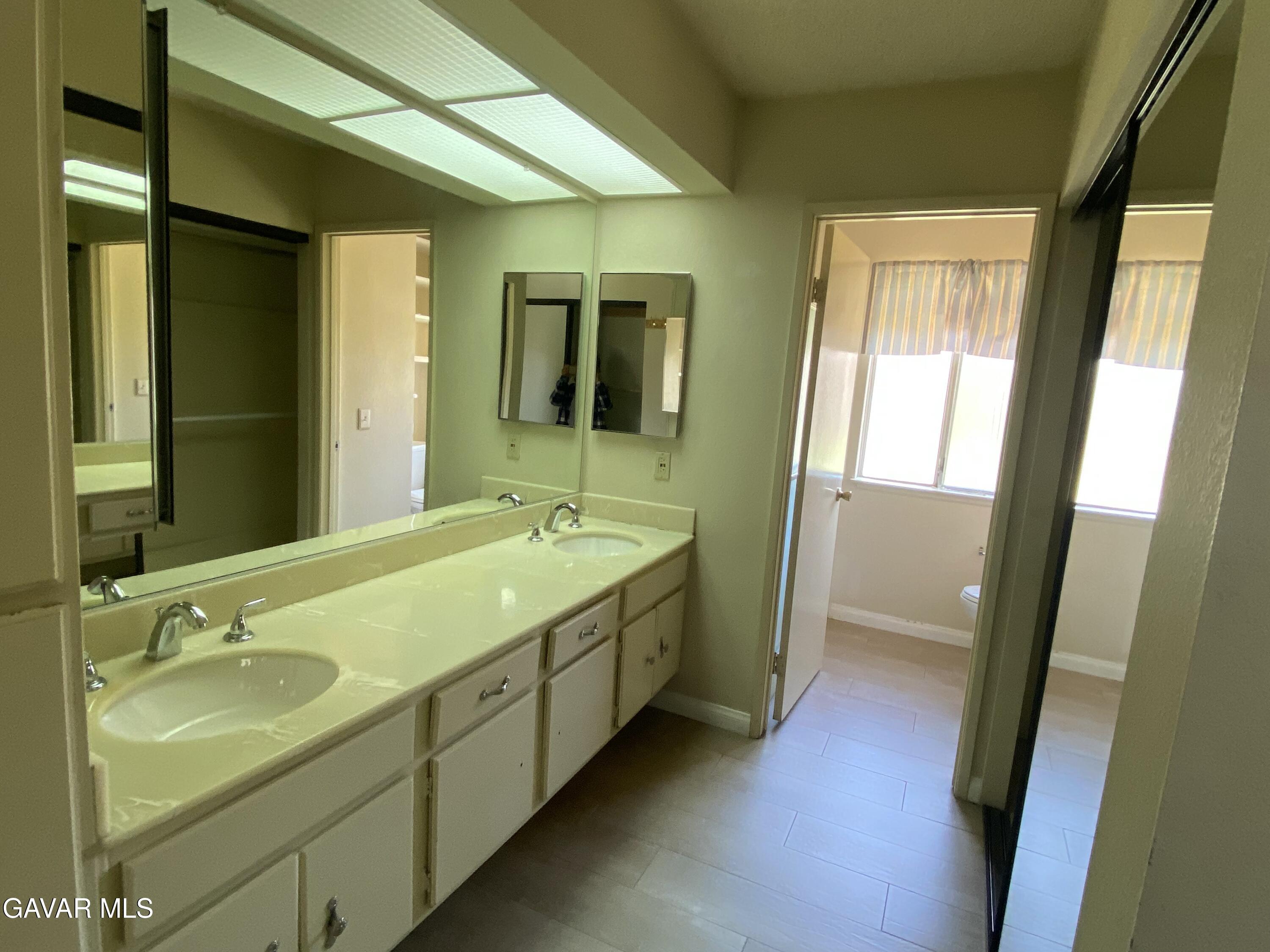 44034 4th Street East Lancaster, CA 93535 - Photo 11 of 14 a bathroom with a double vanity sink and mirror with shower