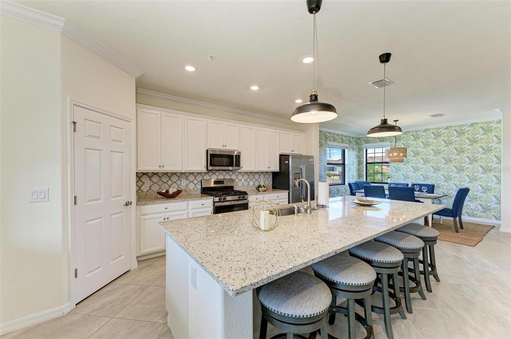 6086 Worsham Lane, Unit 103 Bradenton, FL 34211 - Photo 11 of 60 a kitchen with granite countertop a table chairs stove and refrigerator