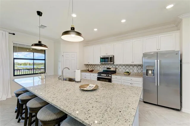a kitchen with stainless steel appliances granite countertop a sink a refrigerator and a stove
