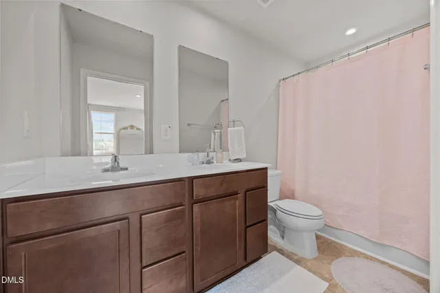 a bathroom with a granite countertop sink a toilet and a mirror