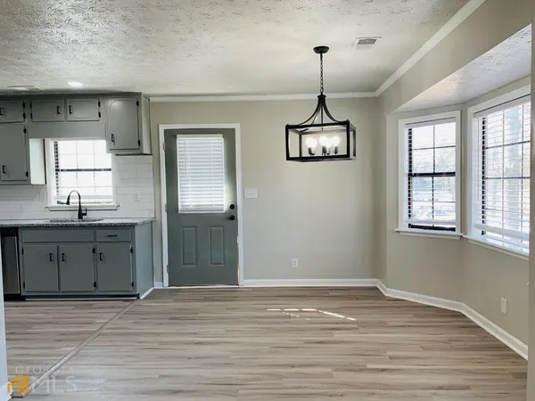 a view of a kitchen with a cabinet a ceiling fan and wooden floor