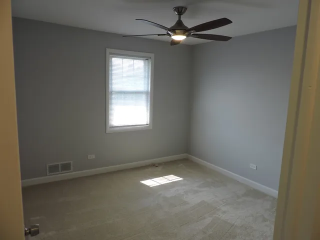 an empty room with a window and a fan