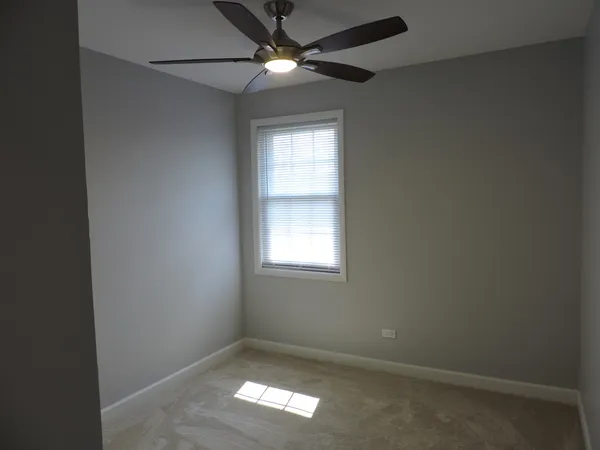 an empty room with a window and a fan