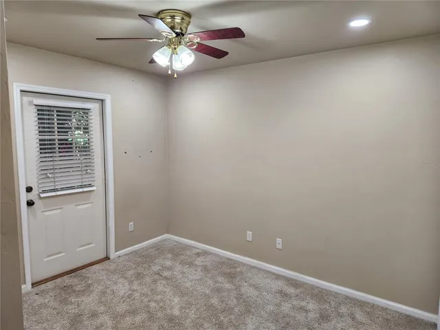 an empty room with a chandelier fan and windows