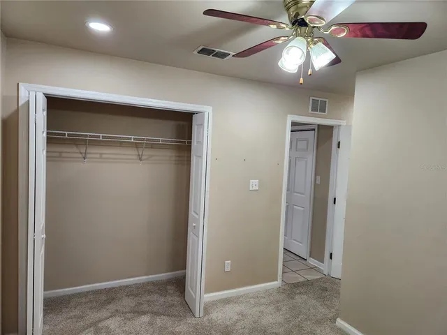 a view of a hallway with a chandelier fan and closet