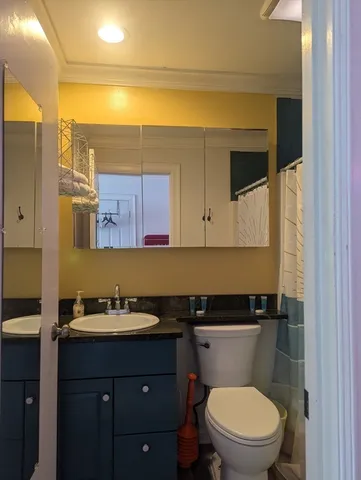 a bathroom with a granite countertop toilet sink and mirror