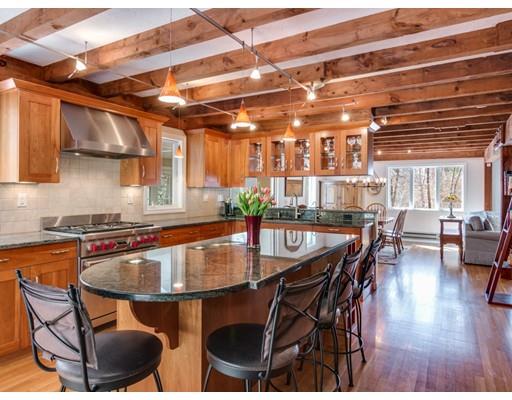 a kitchen with stainless steel appliances granite countertop a table chairs and a wooden floor