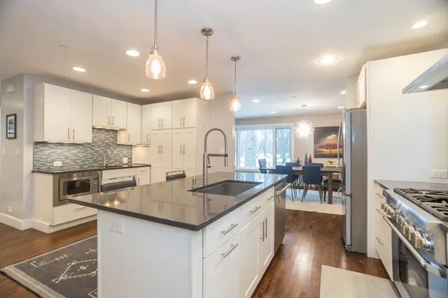 a kitchen with stainless steel appliances granite countertop a sink stove and refrigerator