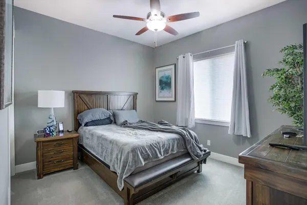 a bedroom with a bed window and potted plant on the dresser