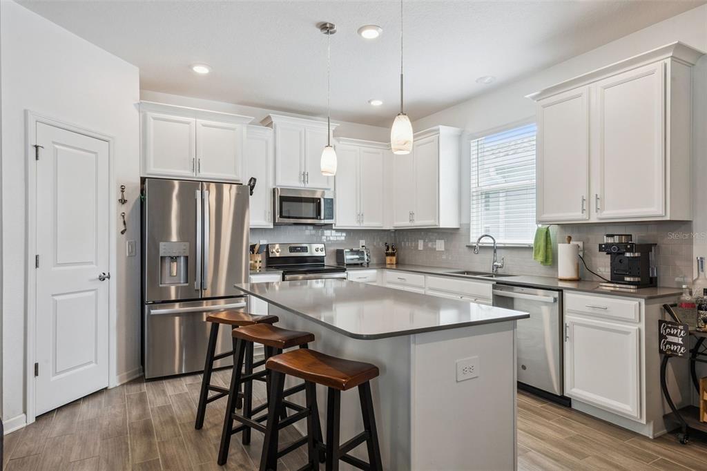 2714 Slash Way St. Cloud, FL 34771 - Photo 19 of 50 a kitchen with stainless steel appliances granite countertop a refrigerator a sink dishwasher a stove and white cabinets with wooden floor