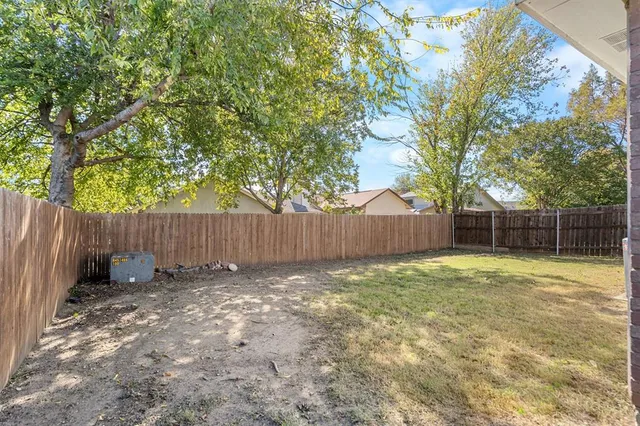 a view of backyard with wooden fence and a large tree