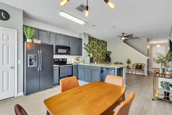a kitchen with stainless steel appliances kitchen island granite countertop a refrigerator a stove a sink dishwasher with a dining table and chairs with wooden floor