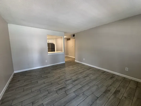 a view of an empty room with wooden floor and a window