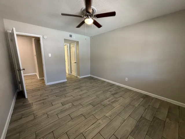 an empty room with wooden floor and fan