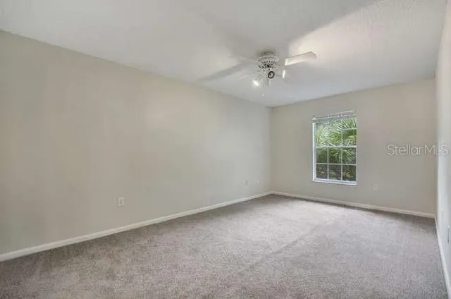 an empty room with a window and a fan