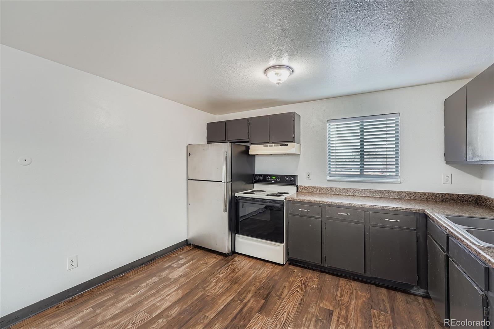 1080 South Eliot Street, Unit 203 Denver, CO 80219 - Photo 5 of 13 a kitchen with stainless steel appliances granite countertop a sink a stove a refrigerator with grey cabinets and wooden floor