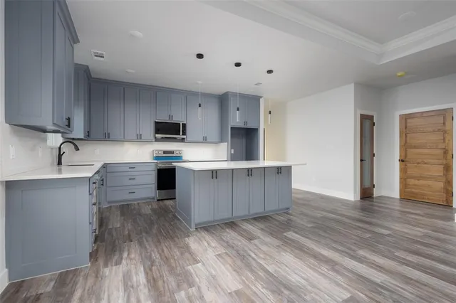 a kitchen with stainless steel appliances a stove top oven a sink and cabinets