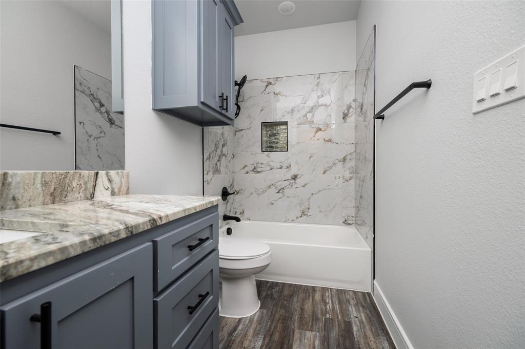 411 West Elm Street Whitewright, TX 75491 - Photo 16 of 31 a bathroom with a granite countertop toilet a sink and bathtub
