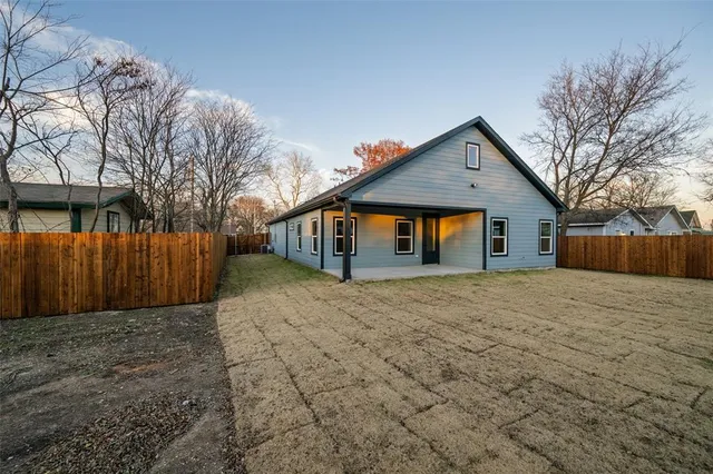 a view of a yard with large trees and wooden fence