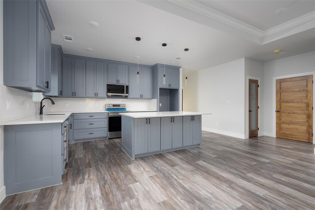 411 West Elm Street Whitewright, TX 75491 - Photo 2 of 31 Kitchen featuring gray cabinetry, stainless steel appliances, a kitchen island, and ornamental molding