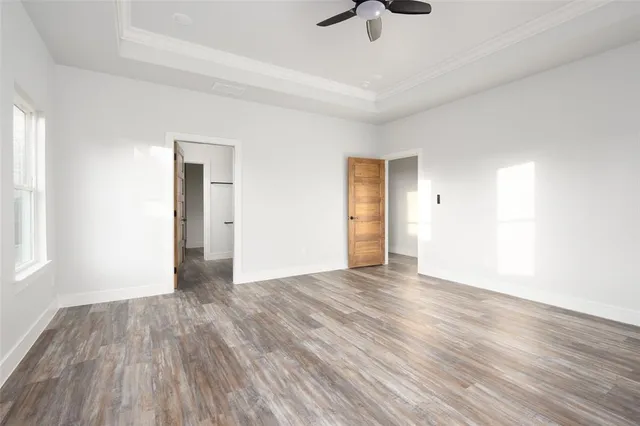 an empty room with wooden floor ceiling fan and windows