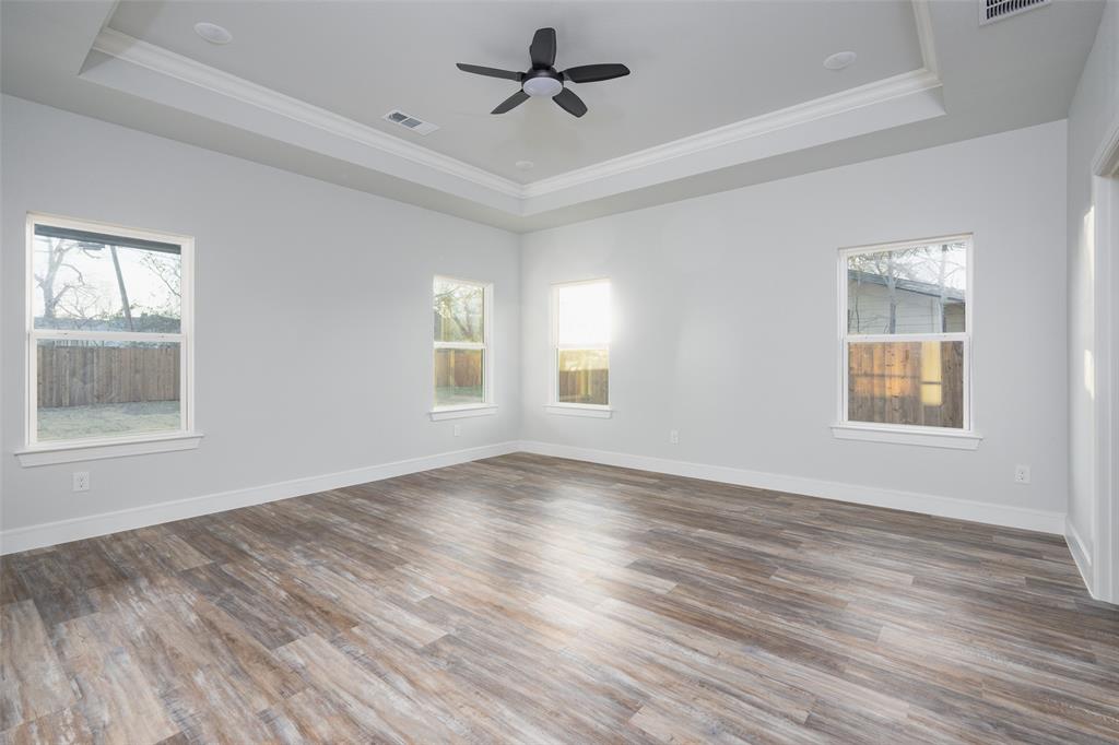 411 West Elm Street Whitewright, TX 75491 - Photo 6 of 31 an empty room with wooden floor ceiling fan and windows