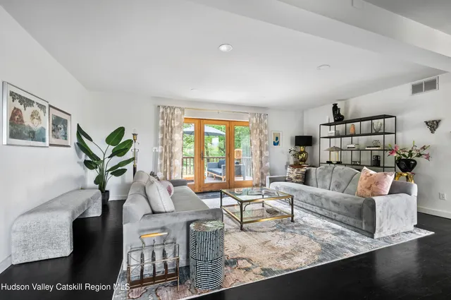 a living room with furniture large window and wooden floor