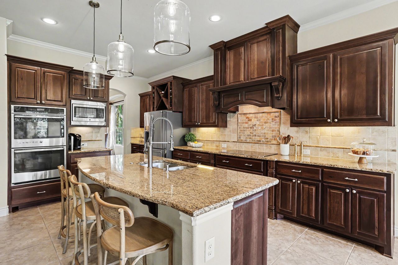 809 Prairie Dunes Drive Georgetown, TX 78628 - Photo 12 of 40 A gourmet kitchen offers rich wood cabinetry, natural stone countertops, and a central island with bar seating.