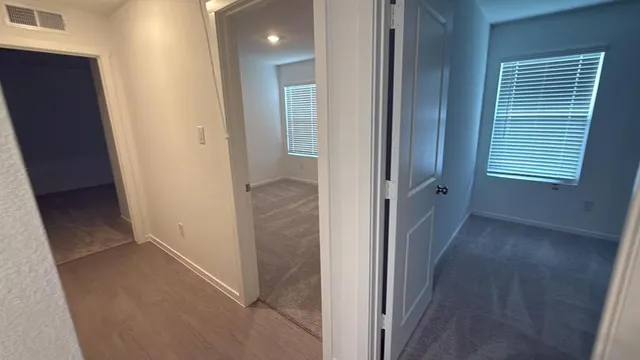 a view of a hallway with wooden floor and a room