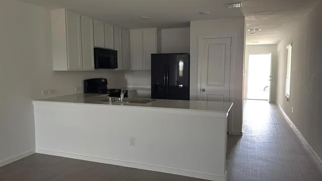 a living room with stainless steel appliances a refrigerator sink and microwave