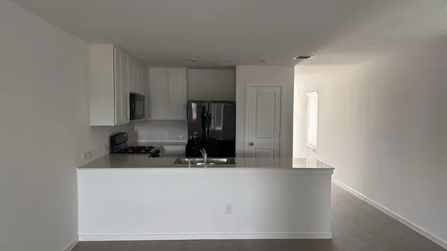 a kitchen with a sink a microwave a refrigerator and cabinets