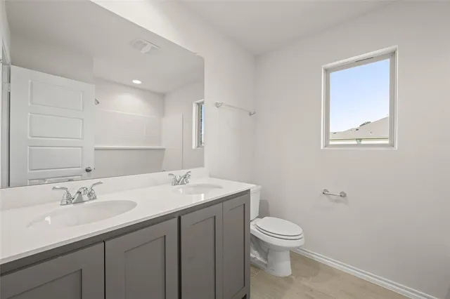 a bathroom with a granite countertop sink a toilet and a mirror