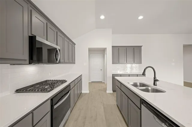 a kitchen with stainless steel appliances a sink a stove and cabinets