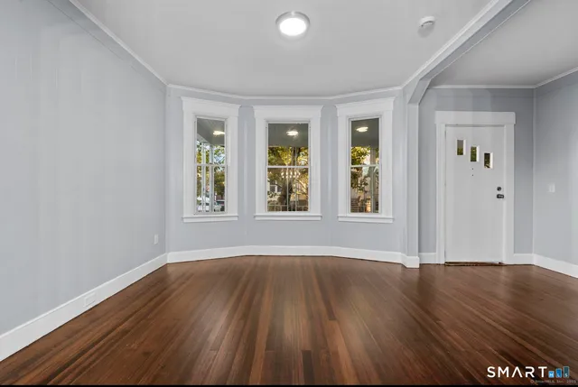 a view of an empty room with wooden floor and a window