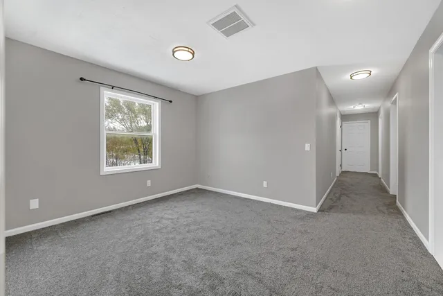 a view of an empty room with windows and closet