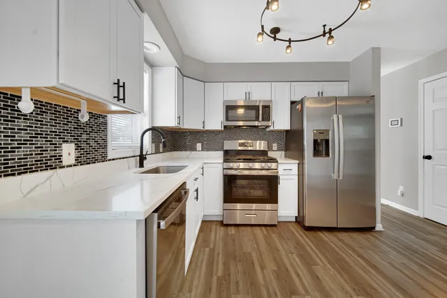 a kitchen with kitchen island granite countertop a sink appliances and cabinets