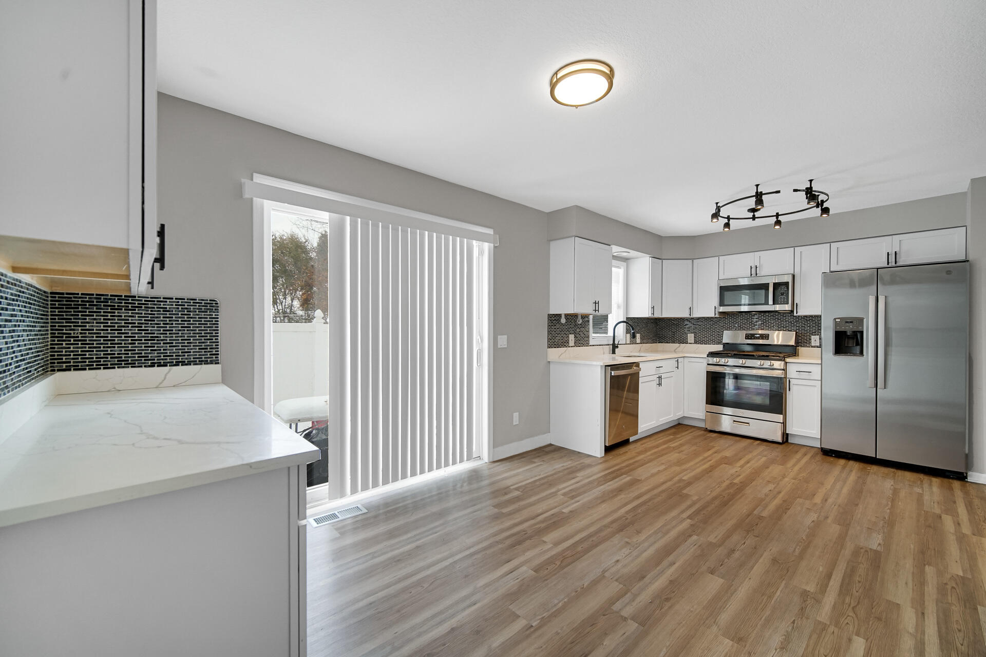 3028 West 15th Avenue Gary, IN 46404 - Photo 27 of 30 a kitchen with granite countertop a refrigerator oven a sink dishwasher and white cabinets with wooden floor