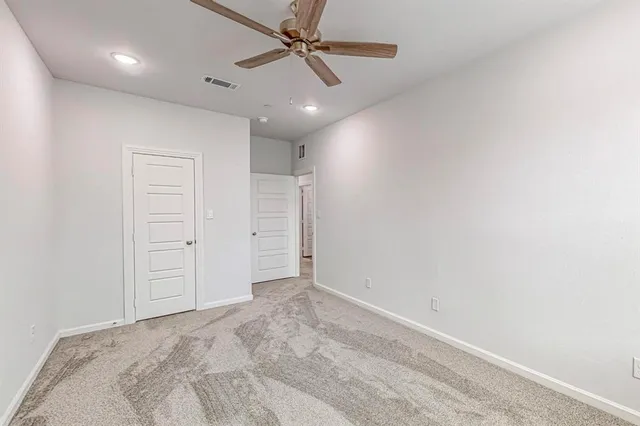 an empty room with closet area and ceiling fan