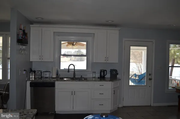 a kitchen with granite countertop white cabinets window and stainless steel appliances