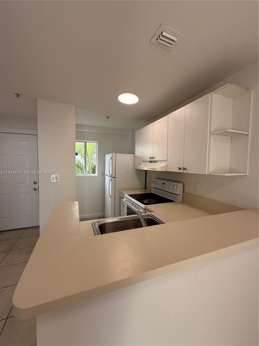 821 Southwest 2nd Street, Unit 7 Miami, FL 33130 - Photo 2 of 29 a kitchen with stainless steel appliances granite countertop a sink a stove and white cabinets with wooden floor