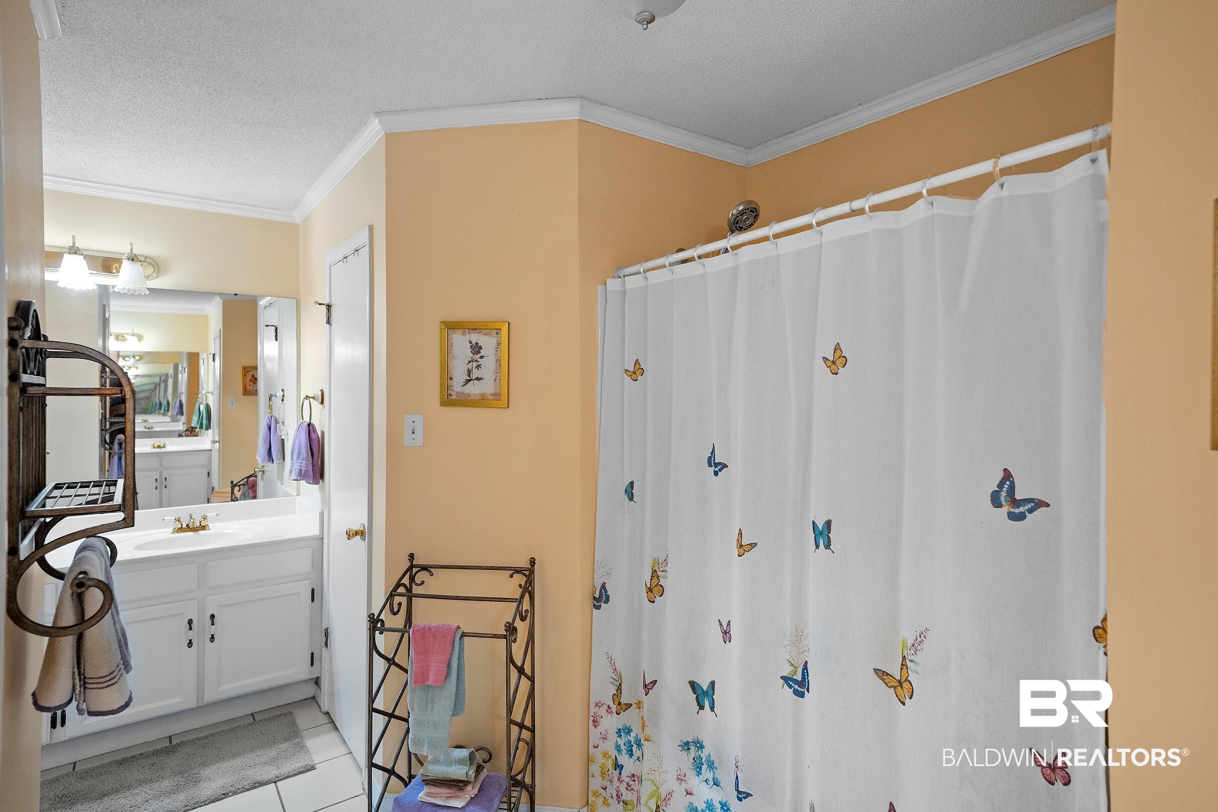 4026 Kingsrow Row Mobile, AL 36619 - Photo 23 of 51 Full bath with vanity, ornamental molding, a shower with shower curtain, light tile patterned flooring, and a textured ceiling