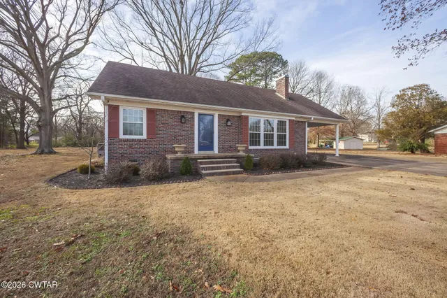 a front view of house with yard and trees around