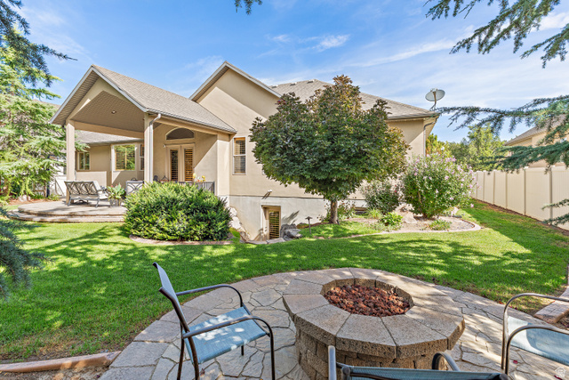 552 East Johns Way Sandy, UT 84070 - Photo 59 of 67 Expansive backyard featuring a stone fire pit, covered patio, manicured lawn, mature trees, and a privacy fence