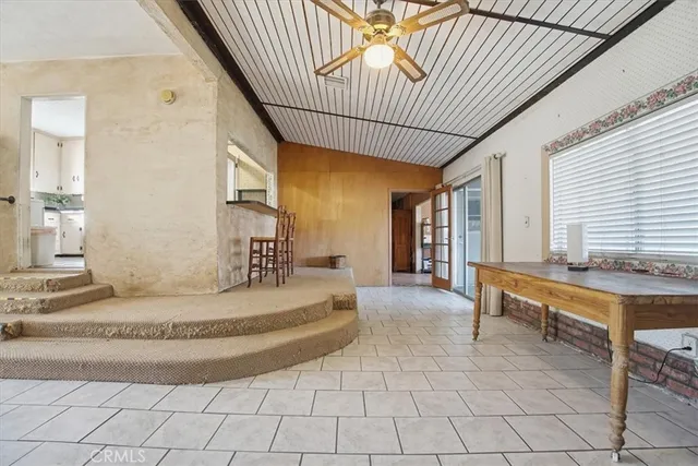 a spacious bedroom with a large bed a chandelier and windows
