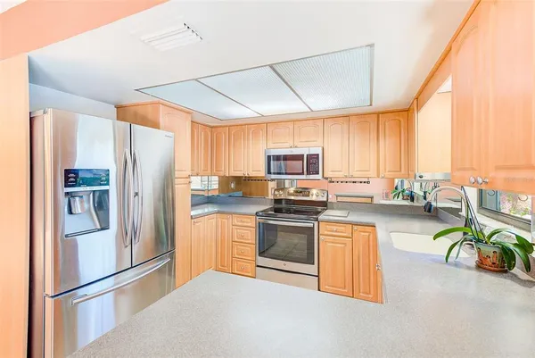 a kitchen with stainless steel appliances granite countertop a refrigerator a stove top oven a sink and dishwasher