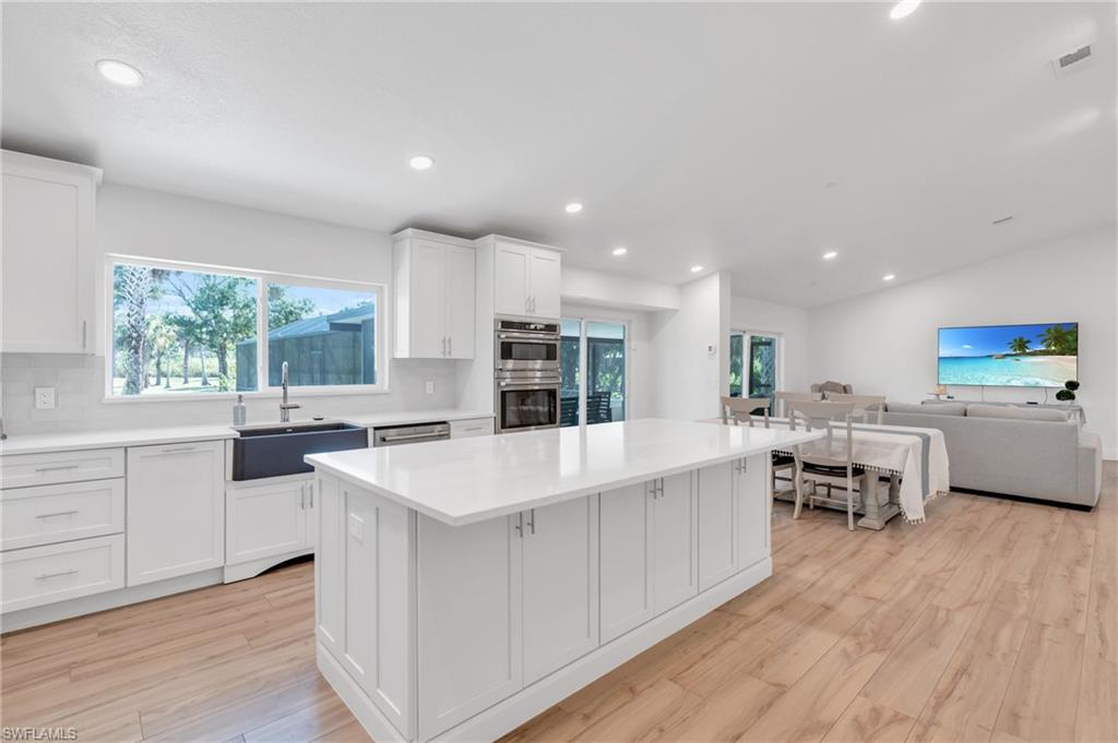 a large white kitchen with kitchen island a large island in it
