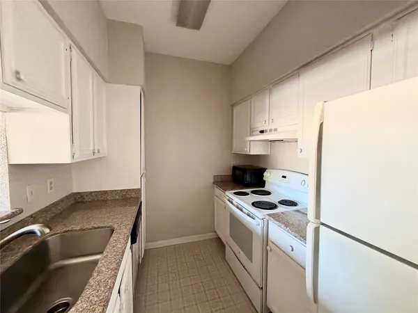 a kitchen with granite countertop a sink and a stove top oven